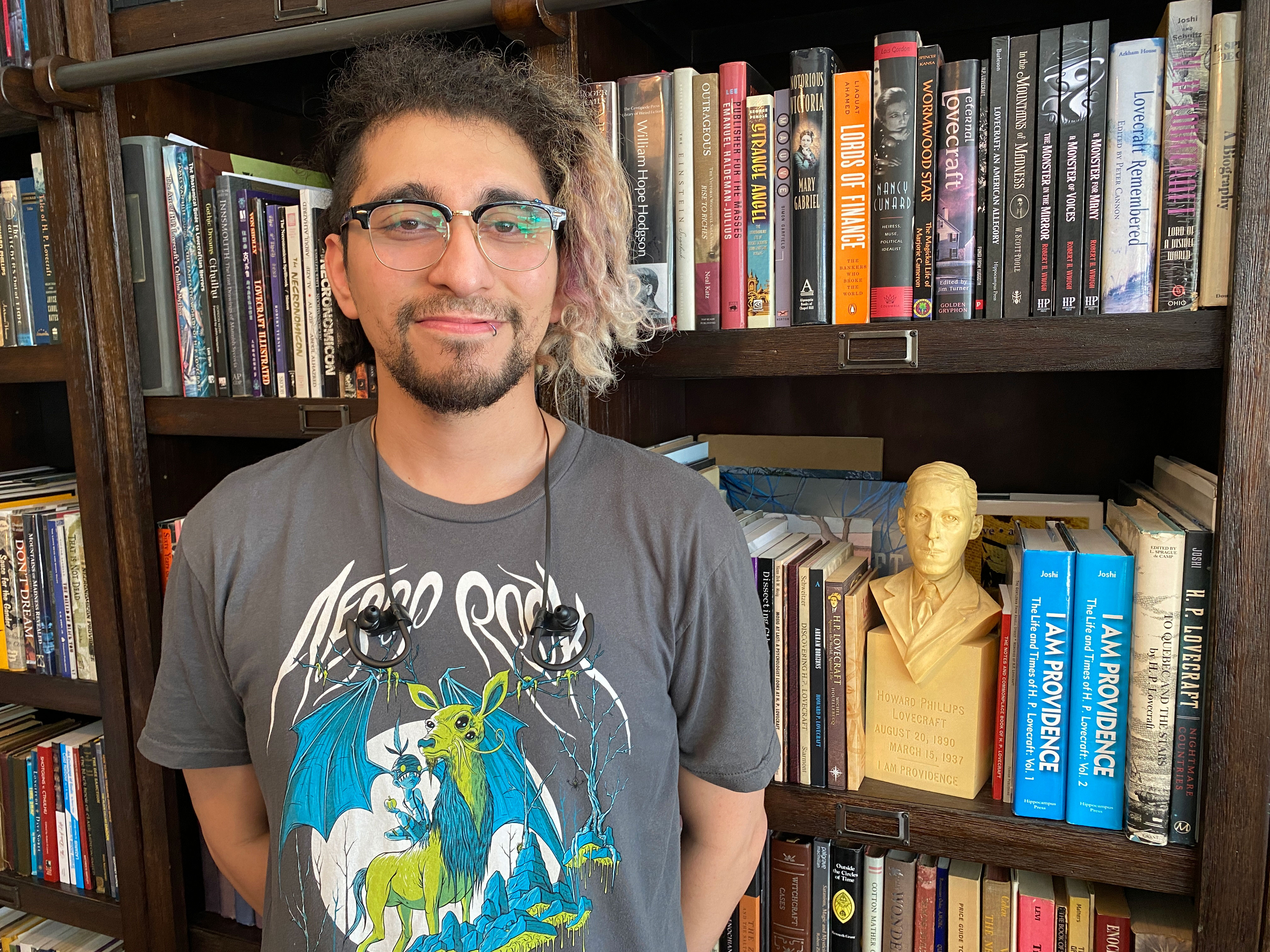 Joshua Nunez in front of our library shelves